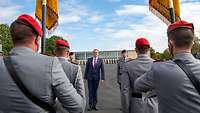 Blick durch die Reihen der Fahnenabordnung: Zwei Soldaten und ein Zivilist in der Mitte stehen vor den Truppenfahnen. 