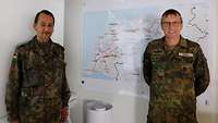 Zwei Soldaten stehen in einem Ausbildungscontainer vor einer Landkarte an einer Wand.