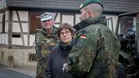 Ein Soldat spricht mit einer Zivilistin, ein zweiter steht im Hintergrund und hört zu.
