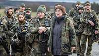 Eine Zivilistin mit Flecktarnparka steht mitten unter Soldatinnen und Soldaten.