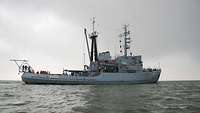 Ein kleines graues Schiff befindet sich auf einen offenen Gewässer.