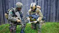 Ein österreichischer und ein deutscher Soldat hocken nebeinander und besprechen sich.