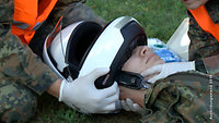 Soldaten nehmen einem verletzten Kameraden den Helm ab