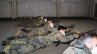 Mehrere Trainingsteilnehmer liegen hinter einem Maschinengewehr und führen die Ladetätigkeiten durch.