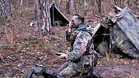 Persönliche Vorbereitung für die Nacht Ein Trainingsteilnehmer verbessert im Biwak seine Gesichtstarnung für die Nacht.
