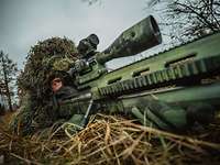 Getarnter Soldat liegend mit Scharfschützengewehr im Anschlag