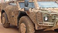 Ein sandfarbenes Militärfahrzeug mit großen Reifen aus der Nähe fotografiert