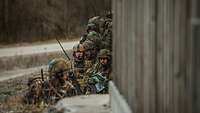 Mehrere Soldaten in Stellung hinter einer Mauer