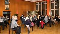 Zivilisten und Soldaten sitzen in einem Hörsaal