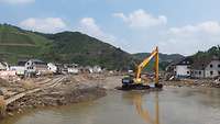 Im aufgewühlten Flussbett der Ahr steht ein gelber Bagger