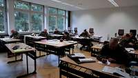 Soldatinnen und Soldaten sitzen in einem Klassenzimmer und lernen.