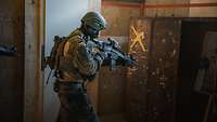 Ein Soldat steht in einem Raum mit seinem Gewehr und zielt auf einen Schrank.