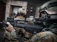 Drei Soldaten stehen vor dem Eingang eines mehrstöckigen Holzhauses vor dem Sturm.