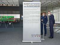 Die Führung der OSLw Zwei Personen vor einem Bild