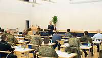 Blick von den Zuhörenden auf einen Luftwaffengeneral vor Podium