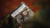 Ein Soldat hält ein Buch mit einem bunten Cover.