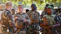 Eine Gruppe malischer Soldaten steht hinter einem deutschen und einem irischen Soldaten