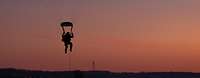 Ein Fallschirmjäger nähert sich im Sonnenuntergang dem Boden.