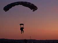 Ein Fallschirmjäger nähert sich im Sonnenuntergang dem Boden.