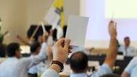 Die Delegierten stimmen mit dem Hochhalten der Stimmkarte bei der Wahl des Katholikenrats