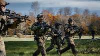 Mehrere Soldaten stürmen über eine Wiese.
