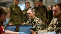 Vor der Blutspende wird der Blutdruck und Puls gemessen und überprüft Zwei Soldaten sitzen zwei weiteren Soldaten gegenüber. Im Hintergrund stehen weitere Soldaten.