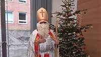 Der heilige Nikolaus vor einem Weihnachtsbaum