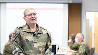 Ein französischer Soldat spricht. Im Hintergrund sitzen Soldaten an Computern und arbeiten