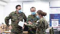 Eine ungarische Soldatin, ein belgischer und ein deutscher Soldat diskutieren ein Manuskript