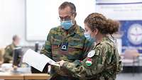 Eine ungarische Soldatin und ein Belgischer Soldat besprechen ein Manuskript