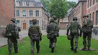 Eine Gruppe von Soldaten läuft nebeneinander zwischen historischen Gebäuden.