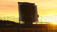 Ein Radar steht in einem Wüstenge-biet vor einer untergehenden Sonne 