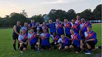 Ein Gruppenfoto der LGAI-Teilnehmer in Trikots, sie halten den Siegerpokal