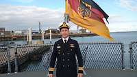 Ribeiro auf dem Flugdeck der Fregatte Bayern, im Hintergrund weht die Deutschlandflagge