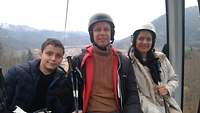 Ribeiro sitzt zwischen seiner Frau und seinem Sohn in einem Skilift, im Hintergrund eine Stadt mitten im Tal