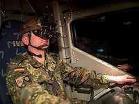 Fahren bei Nacht mit der Bildverstärkerbrille querschnittlich Ein Soldat mit Nachtsichtbrille sitzt am Steuer eines Fahrzeugs.