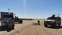 Eine LUNA liegt in der Steppe von Mali auf dem Rücken, ein Fallschirm dahinter. Fahrzeuge sichern rundherum.