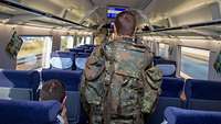 Ein Soldat in Uniform mit Rucksack läuft durch den Mittelgang eines Zuges.