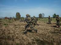 Mehrere bewaffnete Soldaten laufen im Gelände.