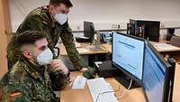 Zwei Soldaten sitzen vor einem Computer.