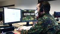 Ein Soldat mit einem Headset vor einem Computer.