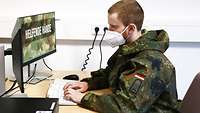 Soldat sitzt vor einem Computer und tippt auf der Tastatur.