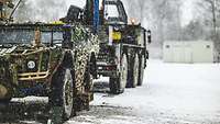 Ein Spähwagen Fennek ohne Hinterrad steht vor einem Fahrzeugkran bei Schnee.