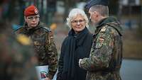 Ministerin Lambrecht spricht mit einem Soldaten. Daneben steht eine Soldatin mit einer Mappe unter dem Arm.