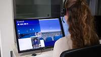 Die Testleiterin spricht mit einem Bewerber am Headset.