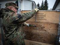Kisten öffnen Ein Soldat benutzt eine Metallschere und schneidet damit eine Metallhalterung durch, die um ein Gebinde platziert ist