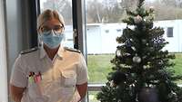 Eine Frau in weißem Hemd neben einem Weihnachtsbaum