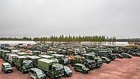 Zusammenführung von Truppe und Material Viele militärische Fahrzeuge (Lkw, Pkw) stehen auf einer freien Fläche eng neben- und hintereinander.