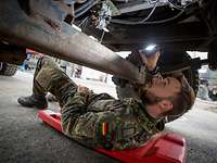 Instandsetzung am Fahrzeug Soldat mit Taschenlampe unter einem Auto