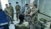 Mehrere Soldaten verschiedener Nationen stehen in einem Raum und werten etwas aus